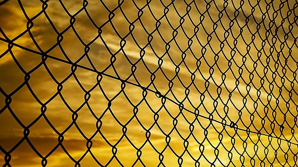 Symbolbild – Grenzzaun im Sonnenuntergang